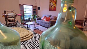 A living room with a sofa, coffee table, and a wooden chair. There are potted plants and a window with a view.