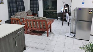 A living room with a sofa set, a dining table, a refrigerator, and a television. - Bula Retreat (Sigatoka)