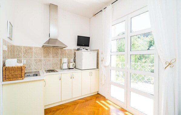 A modern kitchen with white cabinets, a built-in oven, a coffee maker, and a TV on the countertop.