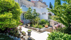 A courtyard with a white building, stone walls, and various potted plants. - Nice apartment in Zaton Veliki with WiFi (Zaton Veliki)