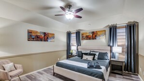 A modern hotel room with a large bed, a ceiling fan, artwork on the walls, and a chair. - 4 Bedroom & Pool: Great Irving Location close to attractions (Irving)