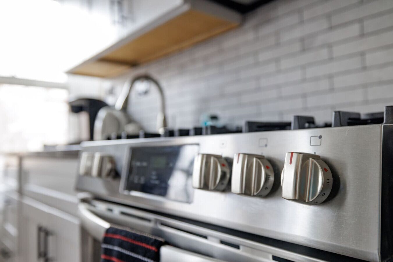 A kitchen with a stainless steel stove, a digital control panel, and a range hood.