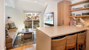 Eine moderne Küche mit einer großen Kochinsel, Barhocker und einem darüber montierten Fernseher.