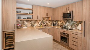 Eine moderne Küche mit Holzausstattung, einer eingebauten Mikrowelle und einer großen Kochinsel.