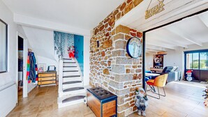 A spacious living area with a stone wall, a staircase, and a dining area with modern furniture. - Gorgeous home in Quessoy with WiFi (Quessoy)