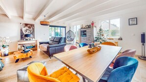 A spacious living room with a wooden dining table, comfortable seating, a hanging chair, and a Christmas tree. - Gorgeous home in Quessoy with WiFi (Quessoy)