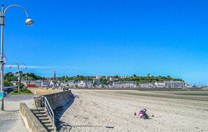 A coastal promenade with a clear sky, a street lamp, and a view of buildings on a hill. - Gorgeous home in Quessoy with WiFi (Quessoy)