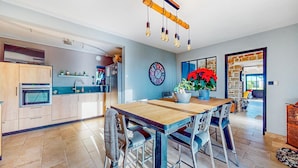 A modern kitchen with wooden cabinets, a built-in oven, and a large dining table with chairs. - Gorgeous home in Quessoy with WiFi (Quessoy)