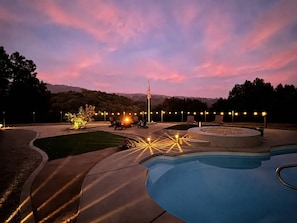 A swimming pool with a sunken seating area, surrounded by a landscaped garden, and an American flag. - Yosemite Retreat w/Pool,Spa,Gold Panning,Bocce,BBQ,Fire pit (Ahwahnee)