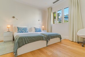 Un dormitorio moderno con una cama grande, lámparas de noche, una ventana con cortinas y vistas al exterior.