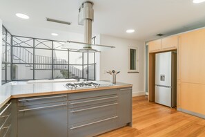 A modern kitchen with a central island, stainless steel appliances, and a view of the upper floor. - Sublime View Villa by Atlantic Holiday (Funchal)