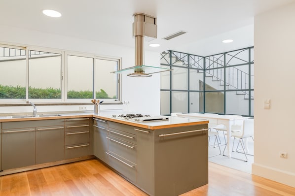 A modern kitchen with a large island, stainless steel appliances, and a glass pendant light. - Sublime View Villa by Atlantic Holiday (Funchal)