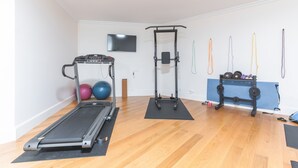 Une salle de sport à domicile équipée d’un tapis de course, d’un banc de musculation et de divers appareils d’exercice.