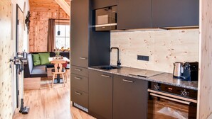 Una cucina compatta con mobili scuri, un forno a microonde, un lavello e un forno.