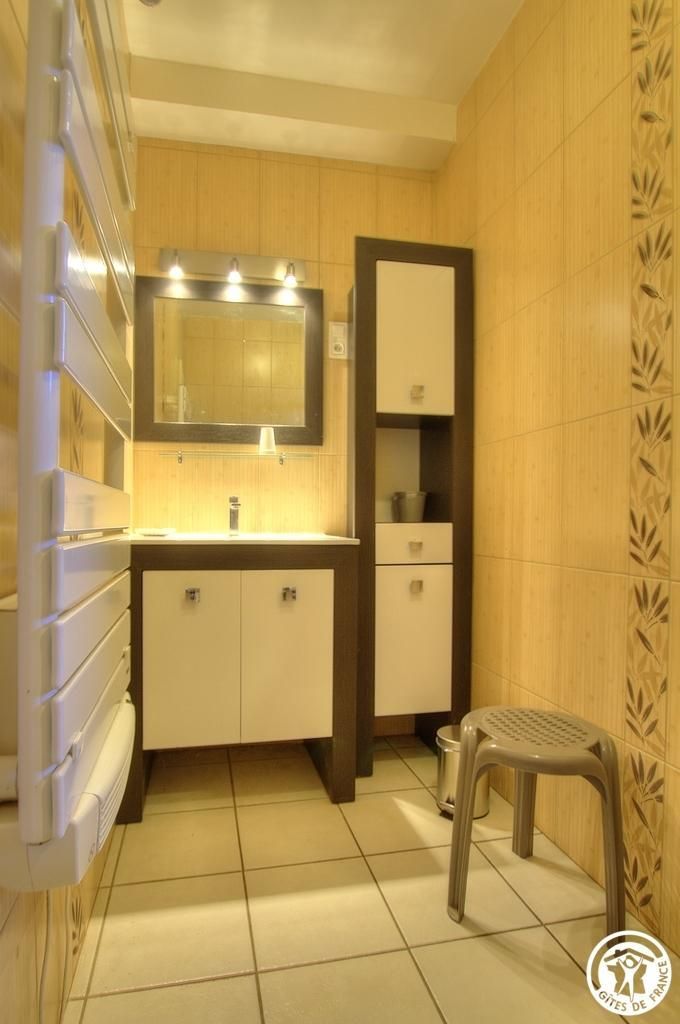 A bathroom with a vanity, mirror, and a stool.
