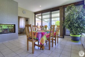 Enjoy meals in this inviting dining area with a large table, comfortable chairs, and a beautiful view of the surrounding greenery.