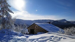 A snow-covered mountain cabin with a clear view of the surrounding landscape.
