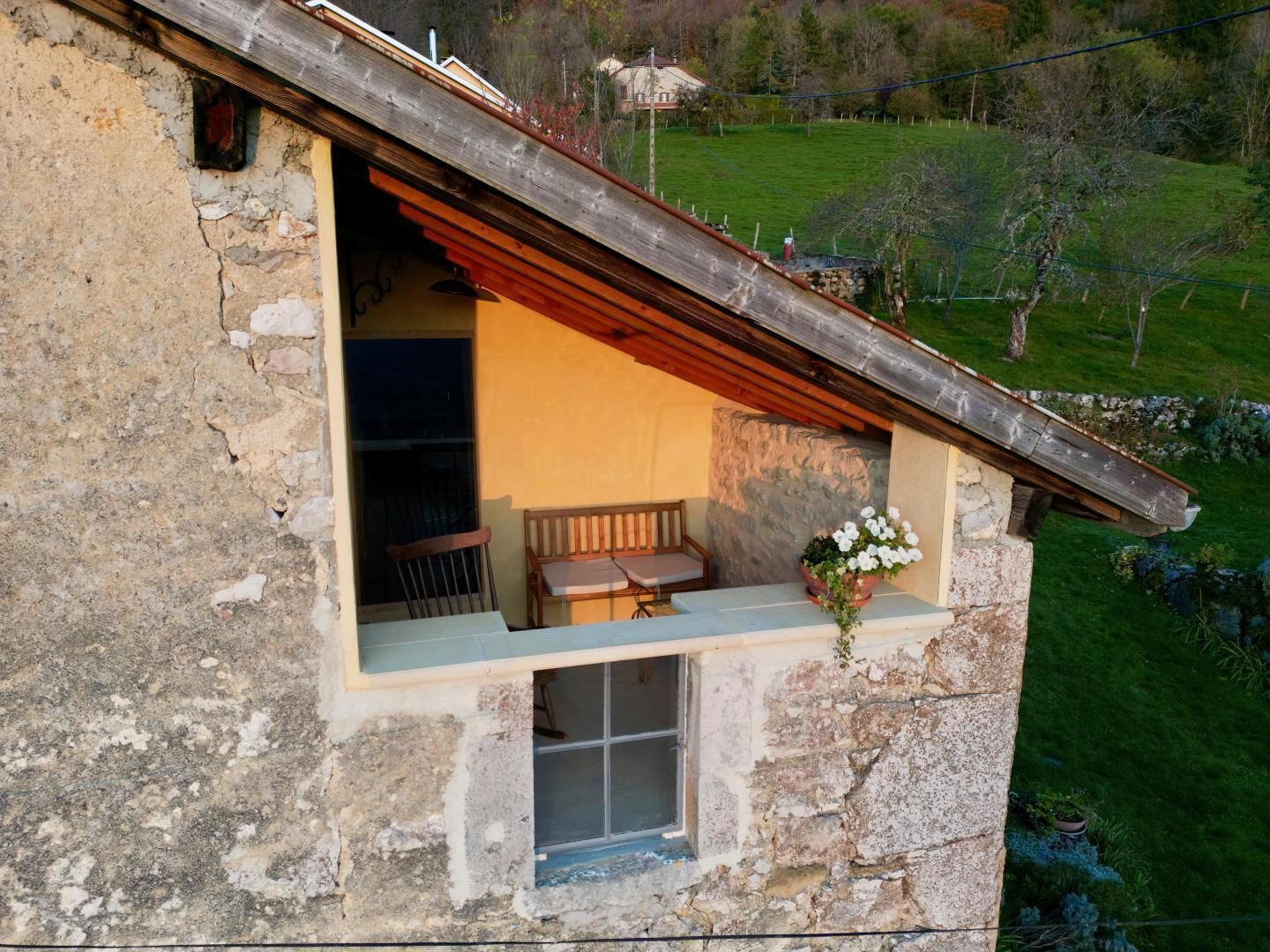 A stone building with a wooden balcony, a bench, and a window.