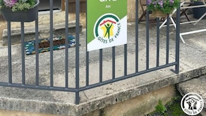 Un edificio rústico con puerta de madera y un letrero que dice "GÎTE AIN GÎTES DE FRANCE".