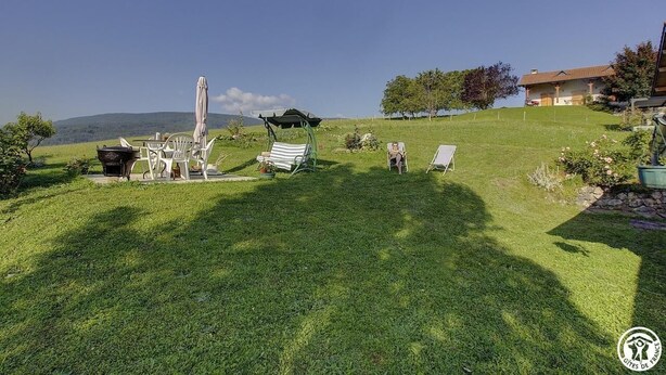 Un espace extérieur verdoyant, doté d’un barbecue, de chaises longues et d’une pergola.