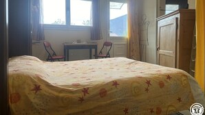 Une chambre à coucher avec un lit, deux chaises, un bureau et une armoire.