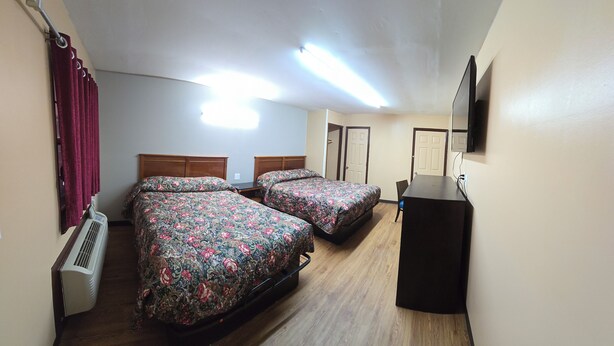 A room with two beds, a desk, a mirror, and a ceiling fan. - Candle Light Motel (Ozark)
