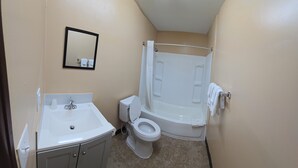 A small bathroom with a sink, toilet, and shower. - Candle Light Motel (Ozark)