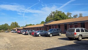 A parking lot with several cars and a building with a brick facade. - Candle Light Motel (Ozark)