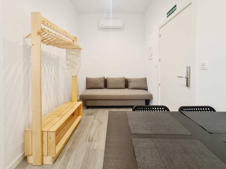 Una habitación pequeña y moderna con un sofá, un banco de madera y una mesita.