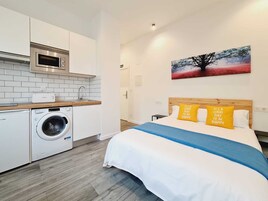 Una camera d'albergo moderna con un letto, un quadro e un angolo cottura completo di lavatrice.