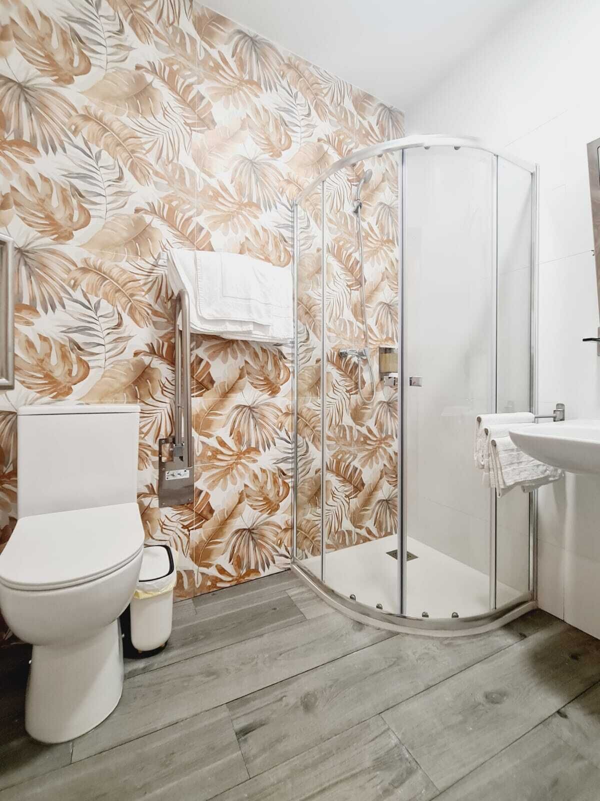 Une salle de bain comprenant des toilettes, un espace douche délimité par des parois en verre et un lavabo.