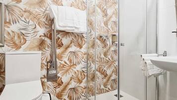 Une salle de bain comprenant des toilettes, un espace douche délimité par des parois en verre et un lavabo.