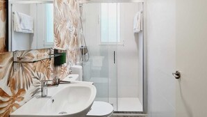 A bathroom with a white sink, toilet, and glass shower enclosure. - Bilbao ROOMS & KITCHEN Irala (Bilbao)