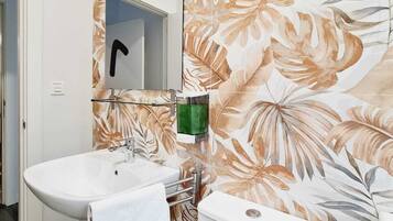 A bathroom with a white sink, a mirror, and a toilet.