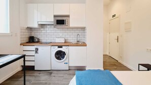 A compact kitchen with white cabinets, a microwave, a washing machine, and a toaster. - Bilbao ROOMS & KITCHEN Irala (Bilbao)