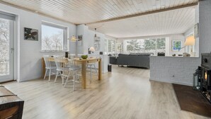 A modern interior with a dining area, a fireplace, and a living room with a sofa and a large window. - Nice home in Nykøbing Sj with WiFi (Nykøbing Sj)