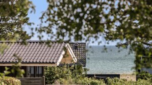 A coastal house with a tiled roof, a wooden deck, and a view of the sea. - Nice home in Nykøbing Sj with WiFi (Nykøbing Sj)