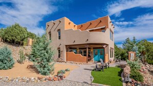 A modern two-story house with a unique architectural design, featuring a curved front porch and a blue door.
