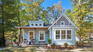 A two-story house with a front porch, a small attached garage, and a well-maintained garden. - Cozy Cottage across the street from Carl Sandburg National Park (Flat Rock)