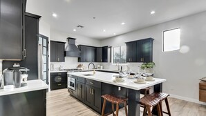 Una cocina moderna con armarios oscuros, una isla grande y un ventanal que proporciona luz natural.