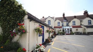 A building with a parking lot, flower boxes, and a clear sky. - Meadows Way Guest House (Uttoxeter)