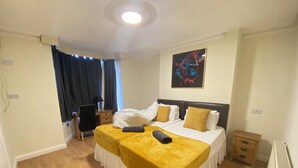 A hotel room with two beds, a desk, a chair, and a large abstract painting on the wall. - Meadows Way Guest House (Uttoxeter)