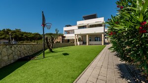 Ett modernt hus i två våningar med en välskött gräsmatta och en basketkorg.