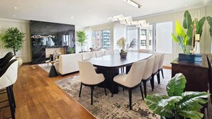 Un comedor moderno con una gran mesa redonda, sillas blancas y piso de madera oscura.