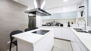 Una cocina moderna con armarios blancos, estufa integrada y espacio para café.