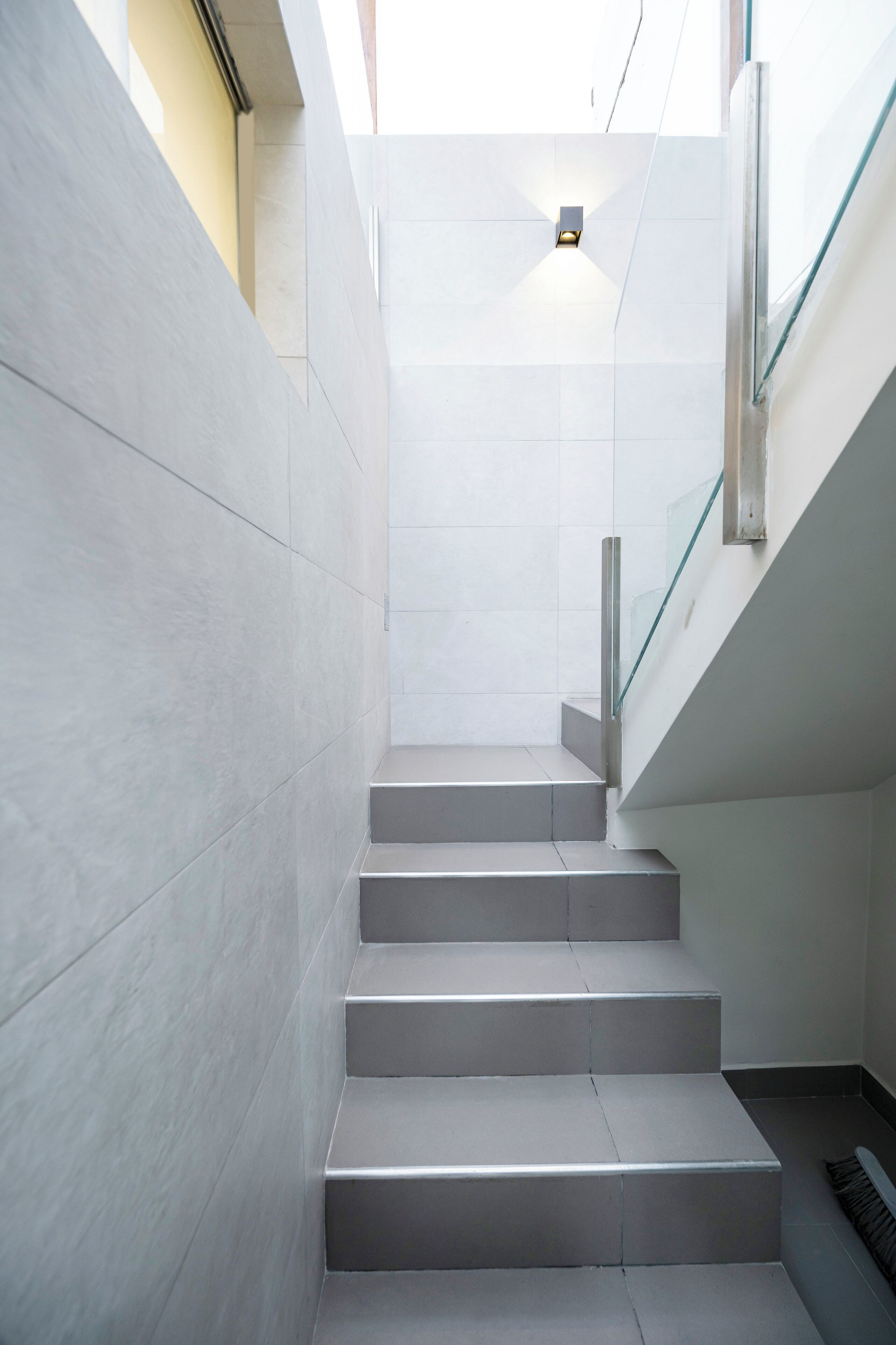 Eine moderne Treppe mit Glastrennwand und einer Leuchte darüber.