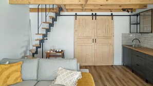 A modern interior with a grey sofa, wooden staircase, and a kitchen area. - Nice home in Sianow with sauna (Sianow)