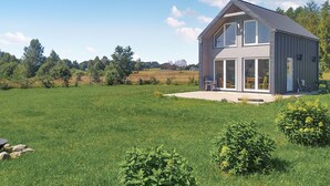 A modern house with a large glass door and windows, surrounded by a grassy field and trees. - Nice home in Sianow with sauna (Sianow)