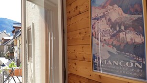 A wooden wall with a poster of Briancon and a door leading to a balcony. - Apartment 'Appartement Deux Chambres' with Mountain View, Private Terrace and Wi-Fi (Briançon)
