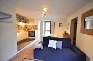 A compact living space with a kitchenette, a sofa, and a dining table. - Apartment 'Appartement Deux Chambres' with Mountain View, Private Terrace and Wi-Fi (Briançon)